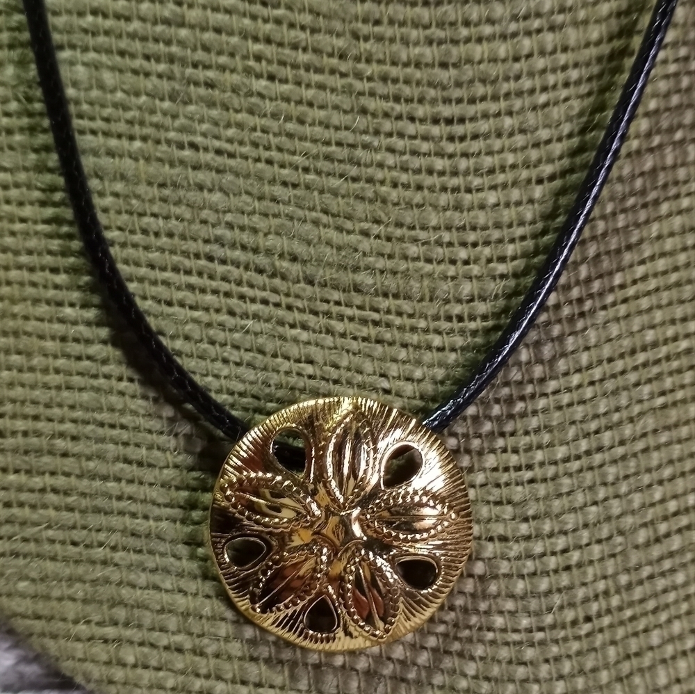 Goldtone sand dollar on black cord necklace